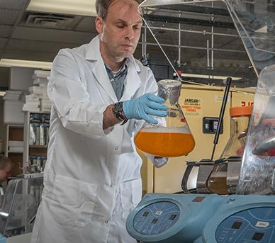 Researcher examines a fluid sample in a lab.